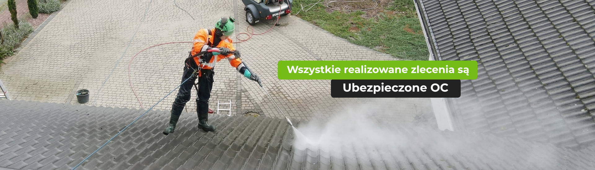 Pracownik w uprzęży bezpieczeństwa myje dach kryty dachówką cementową myjką ciśnieniową. Na zdjęciu napis: Wszystkie realizowane zlecenia są Ubezpieczone OC.